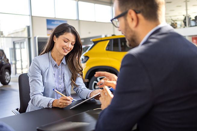 Woman signing for a new car in a car dealership.