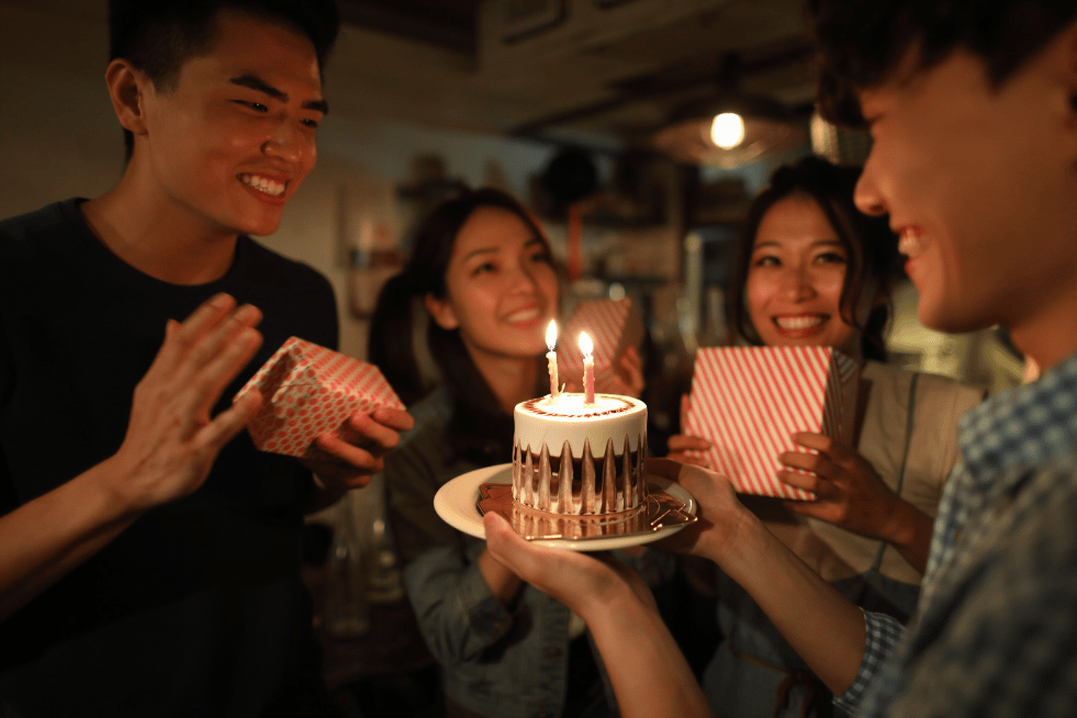 A group of teenagers with a birthday cake and presents