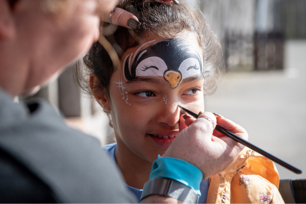 Child having her face painted with a penguin