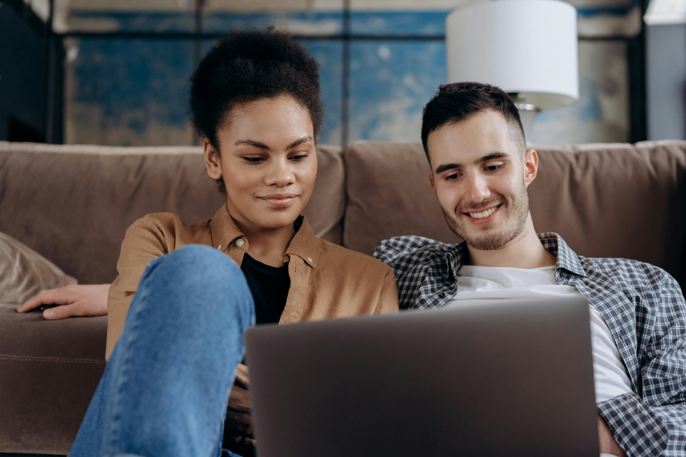 A couple sitting on a sofa looking at a laptop 