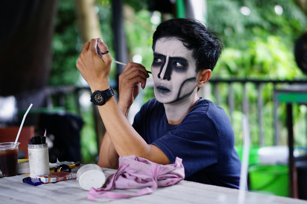Man painting his face with white and black paint 