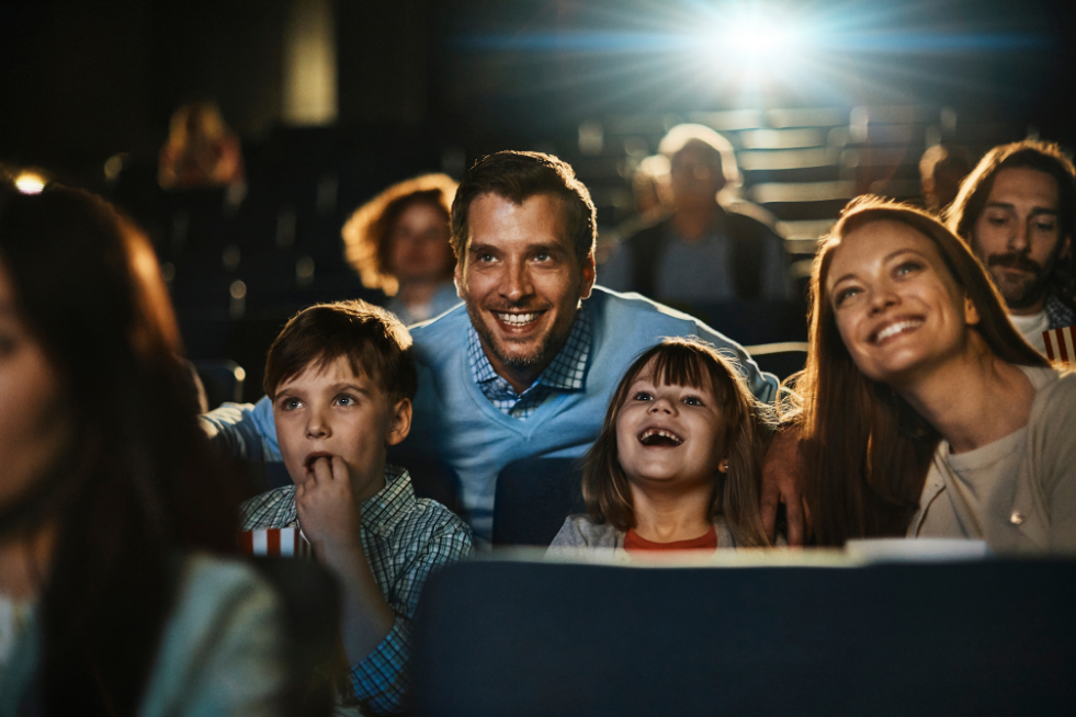 A family of four at the cinema smiling at the screen