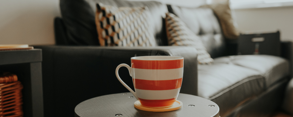 A mug on a side table in front of a sofa