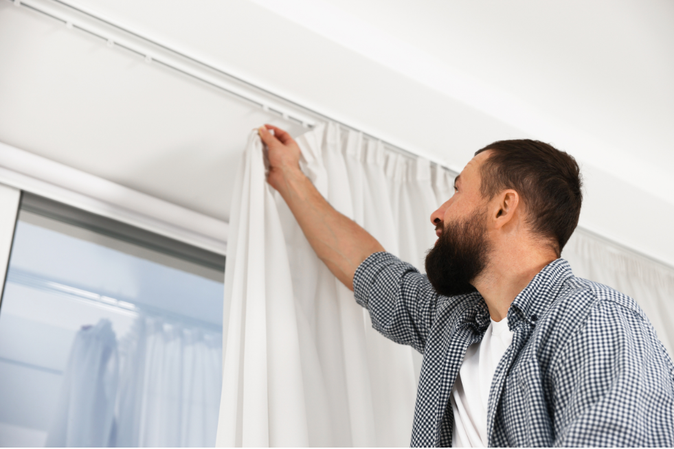 Bearded man pulling back curtain