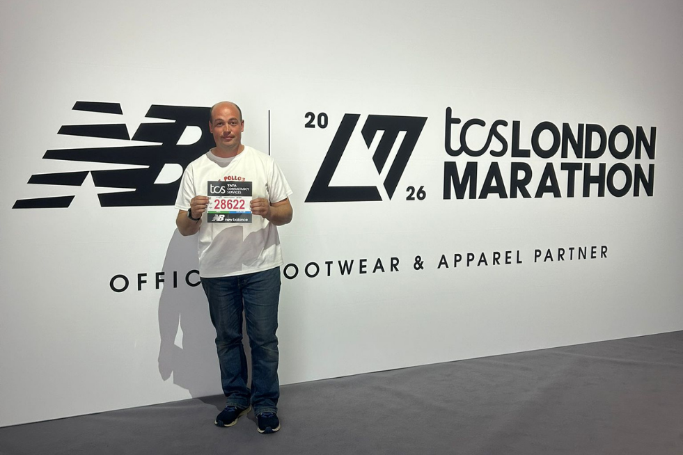 Dave holding up his 2026 marathon bib in front of a TCS London Marathon brand wall