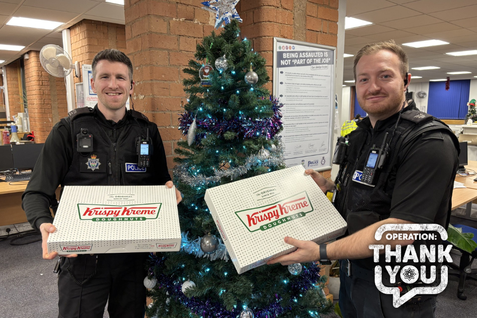 Policemen holding box of Krispy Kreme doughnuts