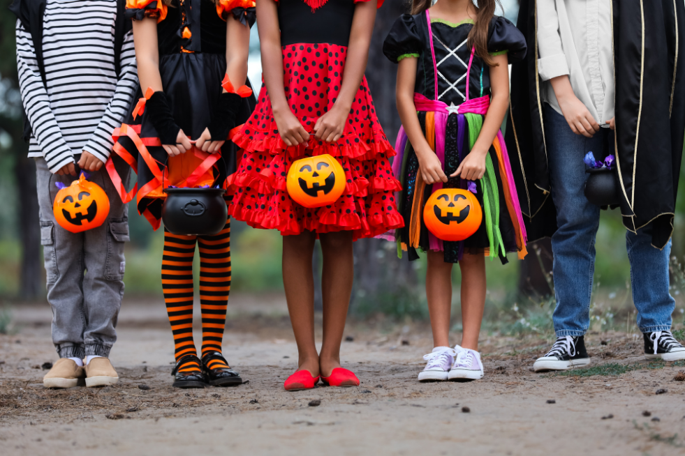 Children in Halloween costumes standing in a row with pumpkin baskets 