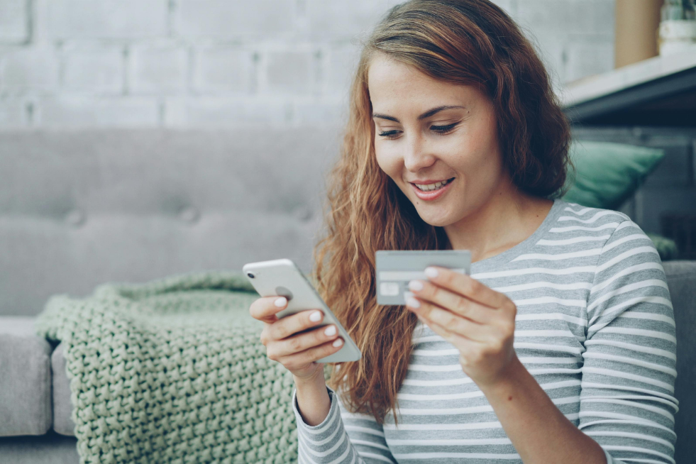 Woman on her phone holding a credit card