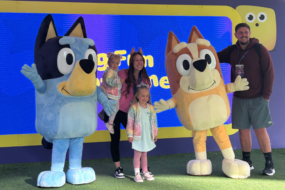 Family of four posing with Bluey and Bingo