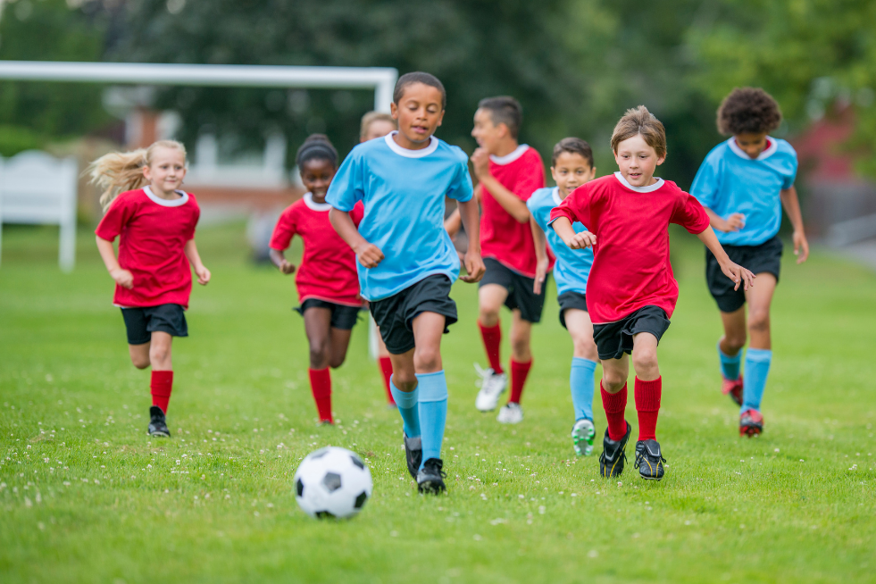 Children in two teams playing football on a field
