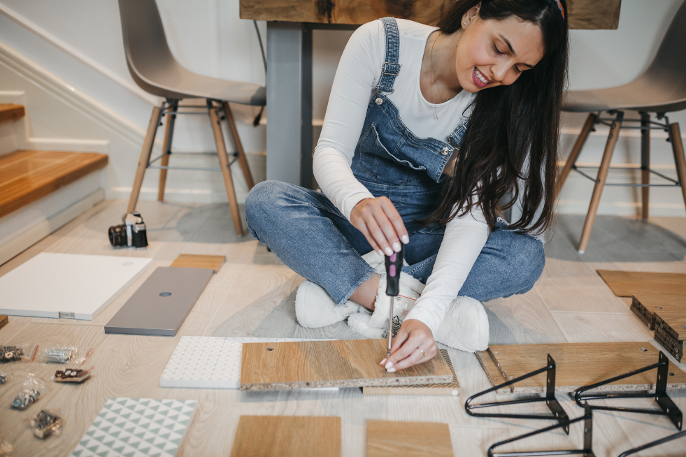 A woman sat on the floor using a screwdriver 