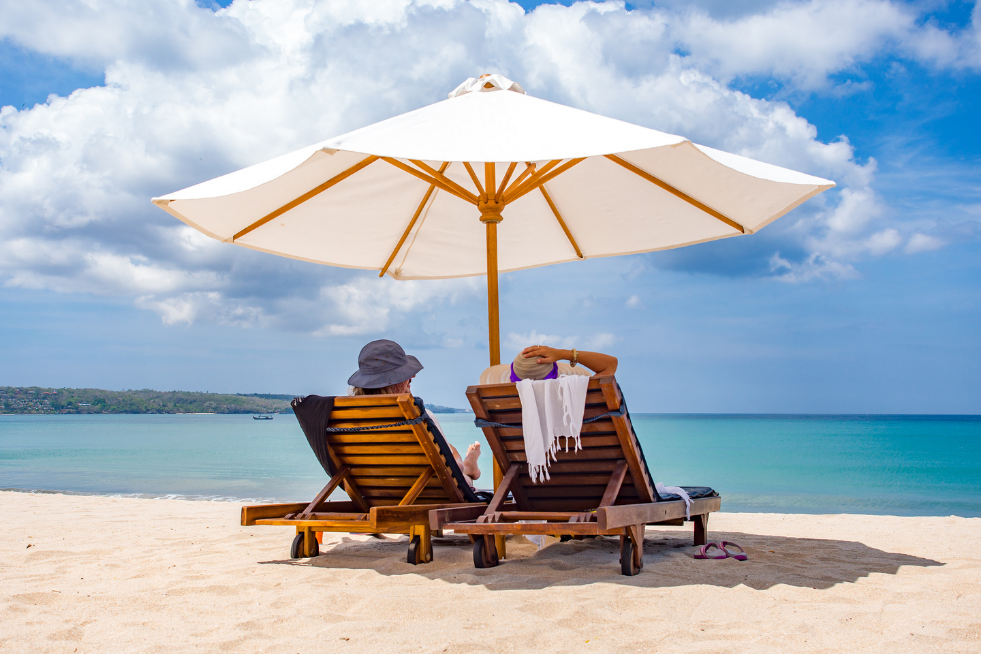 A couple of sun loungers under a parasol on the beach