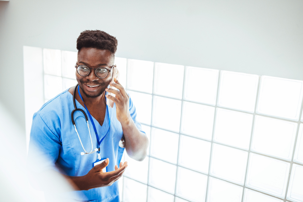 Male nurse smiling whilst on phone call