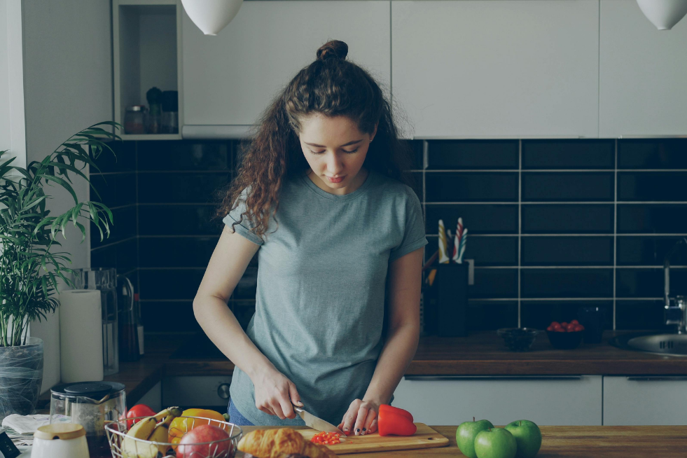 A woman chopping vegetables in a kitchen 