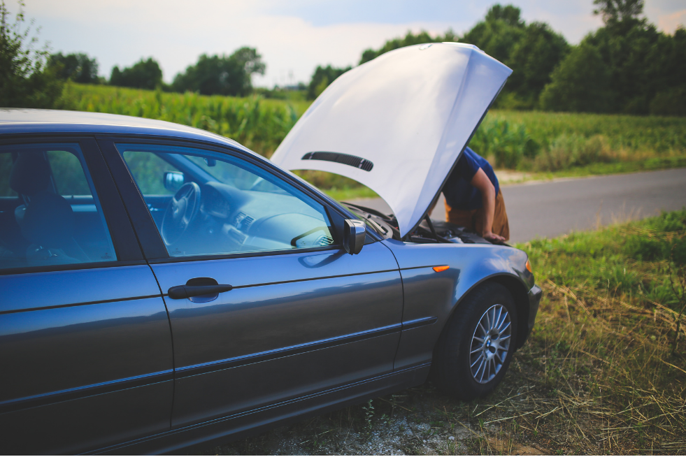 A man looking under the bonnet at the side of the road
