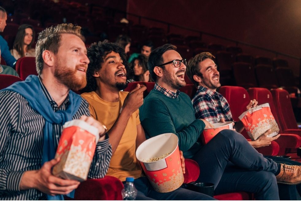 Group of four at the cinema eating popcorn