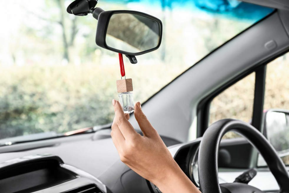 A car windshield with an air freshener bottle hanging from the rearview mirror