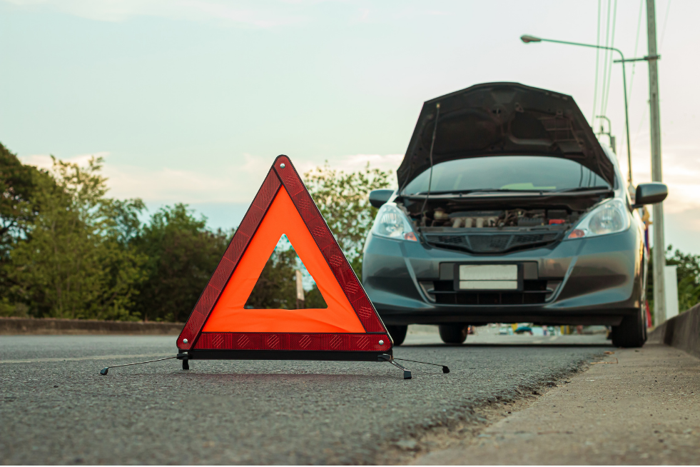 Car at the side of the road with the bonnet up and warning triangle in front